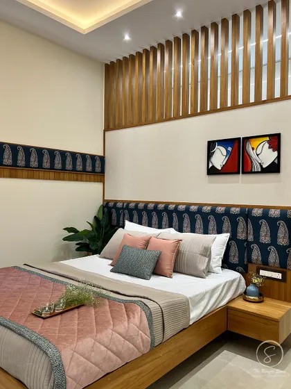 A close-up of the Indian contemporary bed, showcasing the beautiful paisley fabric on the headboard and the clean lines of the wooden bed frame. The look is complemented by modern abstract art.