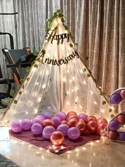 A sweet second-anniversary surprise at home. A canopy tent with fairy lights is set up in the living room, complete with balloons and a light-up number '2'.