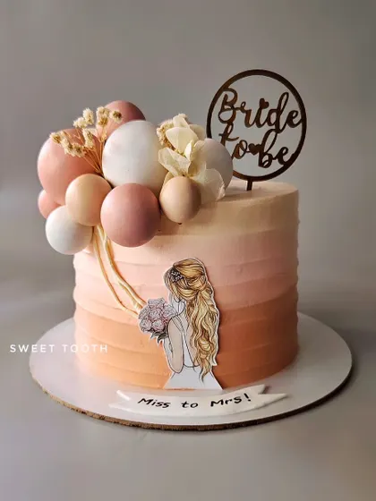 A peachy ombre cake for a bride-to-be, celebrating her journey from Miss to Mrs. This mango cake is decorated with a cascade of chocolate spheres.