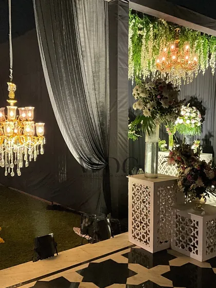 A detail shot of the reception entrance, showing the elegant crystal chandeliers, the black and white flooring, and the jali-work consoles with floral arrangements.
