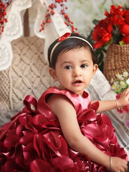I love the rich red of her dress against the natural tones of the boho floral setup. It creates a stunning and vibrant image for her first birthday.