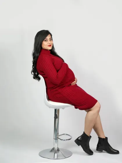 A cool and modern maternity portrait. This mom-to-be rocks a stylish red sweater dress and boots, showing that pregnancy fashion can be chic and fun.