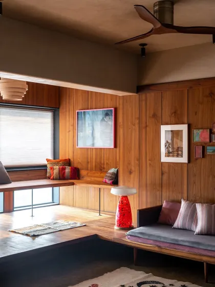The built-in wooden seating by the window is the perfect spot to relax with a book. The design merges the original balcony with the living space, creating a deep connection to the outdoors.