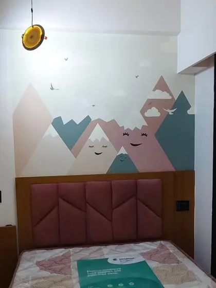 A modern and cute mountain range wallpaper for a kid's room. The smiling mountains and soft pastel colors create a sweet and calming atmosphere above the bed.