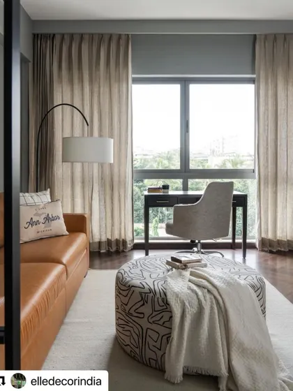 The study area within the family room of the Neutral Chic home. A comfortable leather sofa and a large window make it an inviting space for both work and relaxation.