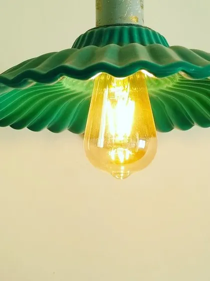 The green pendant lamp, when lit, casts a warm, focused glow. It's an ideal choice for task lighting over a kitchen island or a reading nook, combining functionality with unique style.