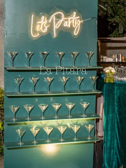 A fun and functional "Let's Party" wall, designed to hold martini glasses for guests. The neon sign added a modern, celebratory touch to the corporate event.