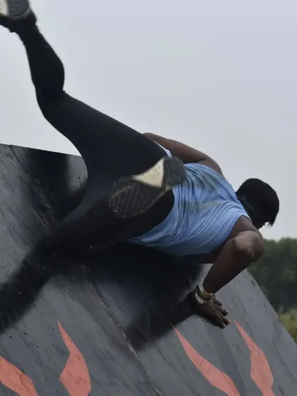 Scrambling over a warped wall at the Wild Warrior race. This requires a combination of speed, agility, and upper body strength.