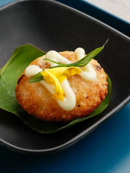 Golden, crispy, and utterly delicious. These Japanese-inspired rice balls are fried to perfection and served on a banana leaf, offering a delightful crunch and a savoury filling.