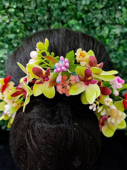 A colorful hair veni with a mix of green, pink, and yellow flowers. This is a wonderful choice for a spring wedding or a vibrant mehendi look.