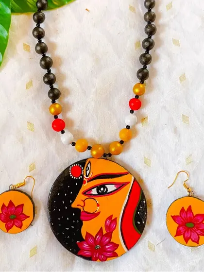 This Durga-themed hand-painted necklace is a bestseller during the festive season. The side profile of the goddess with a lotus is an elegant and powerful design.