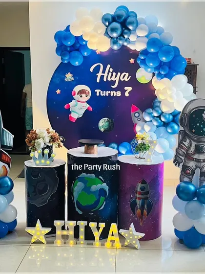 Hiya's 7th birthday was a stellar space adventure. I designed this setup with a galaxy backdrop, astronaut and rocket ship props, and a blue and white balloon arch to create a fun and educational cosmic theme.