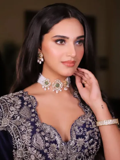 A close-up on this stunning midnight blue Jayanti Reddy lehenga. The shot highlights the intricate silver embroidery and the delicate pearl and emerald choker, showcasing a look of quiet luxury.