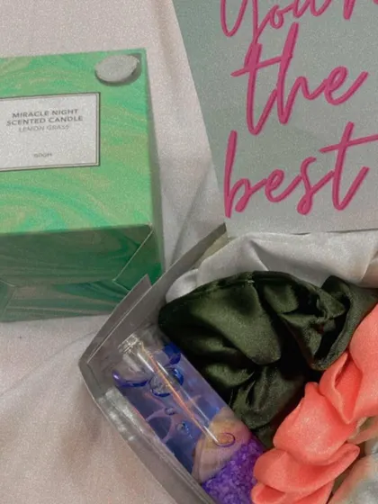 A detailed shot of a mini gift set, featuring a Miracle Night scented candle next to a box filled with scrunchies and a small decorative bottle. It's a perfect little pick-me-up gift.