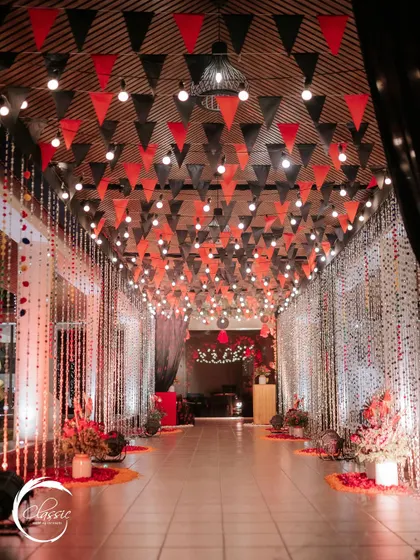This hallway was transformed into a festive walkway with a ceiling of red and black pennant banners, string lights, and shimmering curtains, building anticipation for the party ahead.