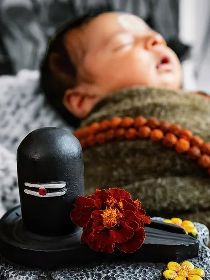 A creative shot with a selective color effect, highlighting the Shivling and the sacred flower. This artistic approach adds a unique and dramatic touch to the newborn portrait.