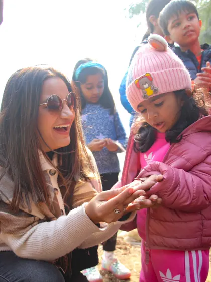 A mother shows a young girl an earthworm, teaching her about the important role they play in creating healthy soil. It's a great hands-on science lesson.