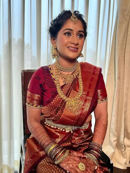 A classic Muhurtham look for a South Indian bride. The makeup is kept timeless with a focus on radiant skin and a soft lip, allowing the rich maroon saree and temple jewelry to be the stars.