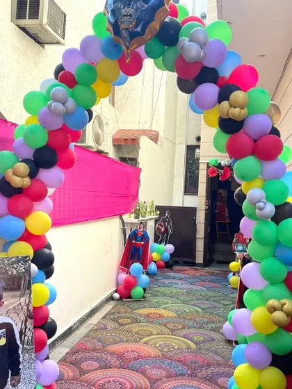 The entrance to a superhero-themed party, with a colorful balloon arch and a welcome photo of the birthday boy.