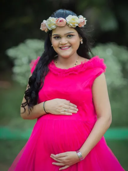 A joyful close-up portrait of a mom-to-be in a bright pink gown, her smile lighting up the photo.