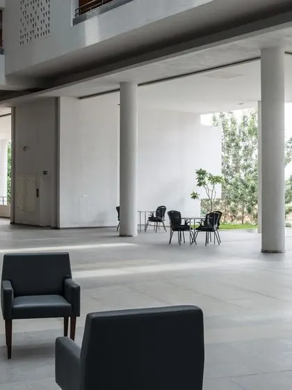 Another view of the expansive, column-supported common area on the ground floor. The seamless connection to the outdoor landscape and ample seating make it a popular gathering spot for residents.