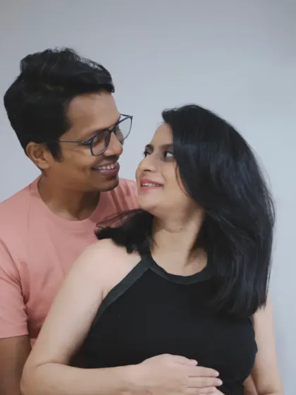 The couple shares a happy, knowing look in this candid at-home portrait, their smiles reflecting their excitement.