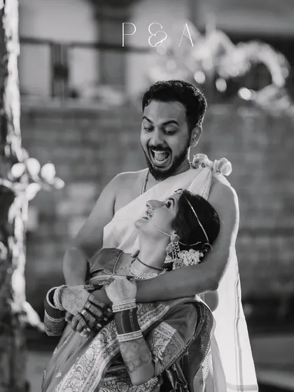 A playful and candid black and white shot of the couple, capturing their fun-loving personalities amidst the traditional setting.