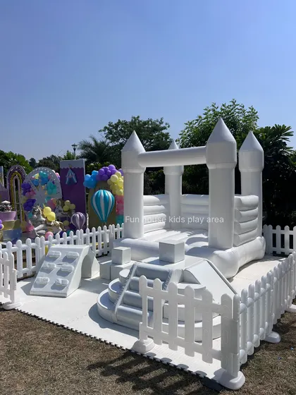 A full view of the white bouncy castle and soft play climbers, perfect for an outdoor party with plenty of space to run and play.