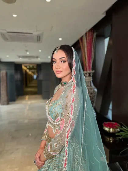 A side profile of the modern bride, showing how her soft open waves and dupatta draping create a dreamy and romantic silhouette.