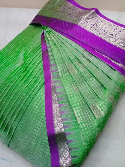 A bright green saree with a purple and silver border. The pleats are crisp and the saree is ready to be draped in minutes.