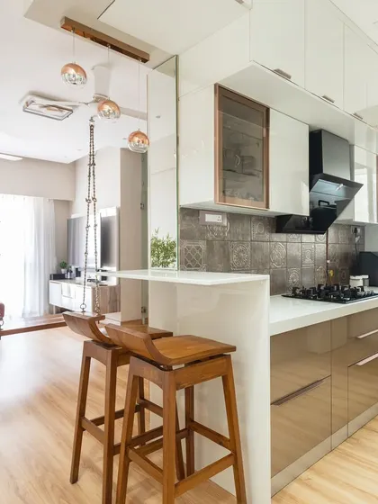 An open-concept kitchen with a breakfast bar that connects to the living area. The white and beige cabinets create a seamless flow between the two spaces.