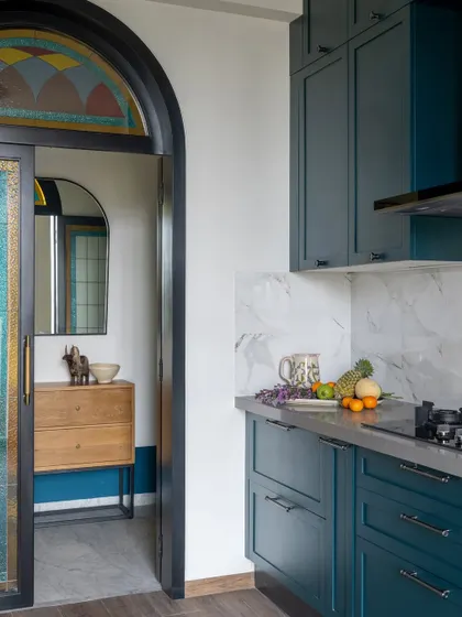 The custom arched door with stained glass is a standout feature of the Bombay Blue kitchen. It frames the entry and adds a unique, artistic touch that is reminiscent of vintage design.