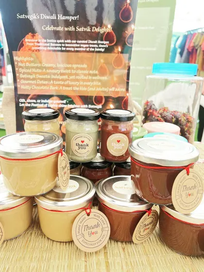 A display of my desserts and spreads at a local market. You can see jars of my chocolate mousse and rabdi, alongside various nut butters, all with "Thank You" tags for my customers.