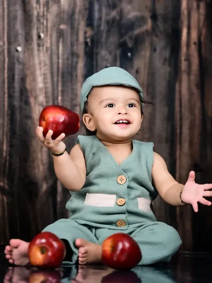 A happy baby boy holding an apple.