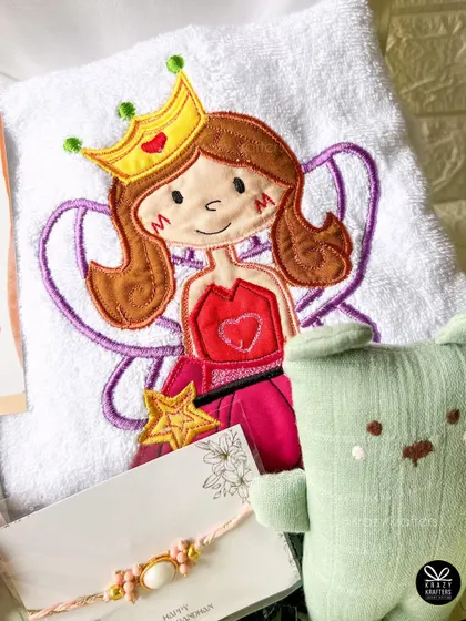 This Rakhi hamper for a little sister includes a beautifully embroidered towel with a fairy princess, a soft toy, and a delicate rakhi bracelet.