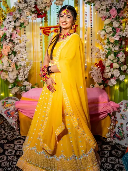 A full-length shot of the bride at her Haldi, standing in front of the beautiful floral and drape backdrop I designed for her.
