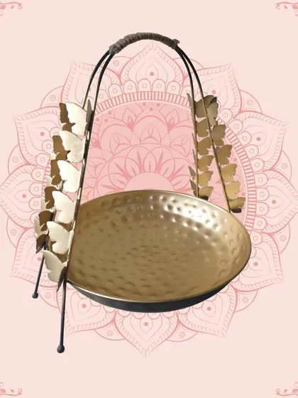 This unique golden platter with butterfly-adorned handles is a whimsical and stylish piece. The hammered texture of the bowl adds to its artisanal charm.