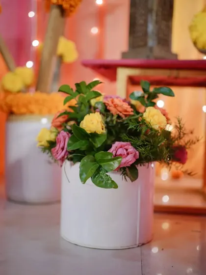 A close-up of a floral centerpiece with pink and yellow roses, part of the vibrant decor for a Mehendi ceremony.