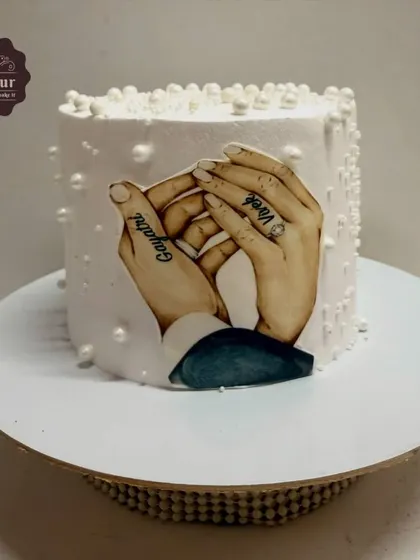 A simple yet heartfelt anniversary cake featuring an edible print of the couple's hands with their names tattooed. The cake is finished with delicate sugar pearls, proving that a personal touch can be very powerful.