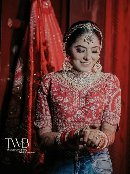 A smiling bride getting ready. This shot captures her happiness as she adjusts her bangles, blending the traditional bridal look with a modern, candid feel.