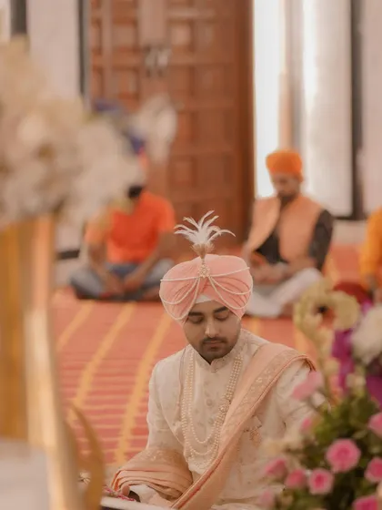 The groom sits in prayer during the ceremony, a moment of reverence and reflection captured with a soft, respectful focus.