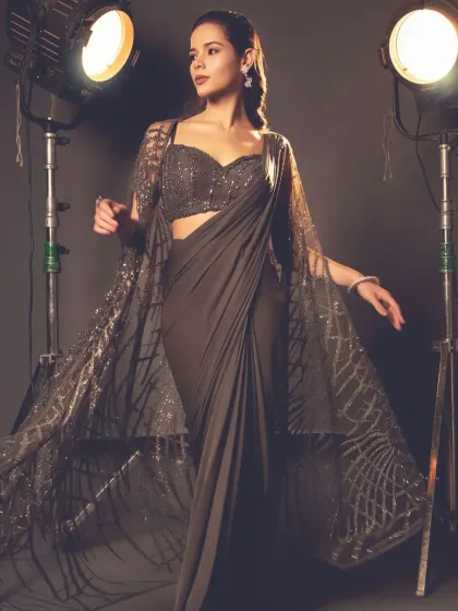 Where contemporary meets tradition, the cape saree steals the spotlight. This grey-brown version features a long, flowing cape with intricate web-like embroidery.