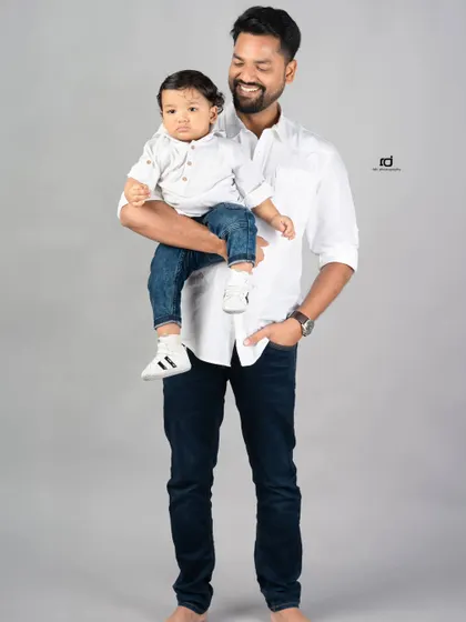 A father holds his son, a perfect picture of a proud dad. This classic portrait captures the quiet strength and love of a father.
