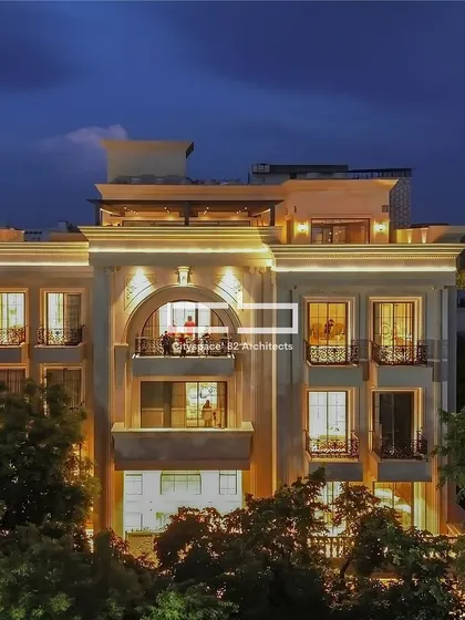 This facade blends modern design with classical accents, featuring ornate mouldings and clean lines for a striking visual balance. An elegant arched window introduces dynamism, while thoughtful lighting accentuates the architectural details at night.