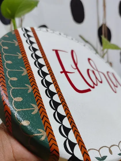 A side view of the "Elara" name plaque, highlighting the layered, hand-painted patterns in green, black, and gold that give the piece its depth.