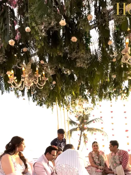 A beautiful moment under the lush floral canopy of the seaside mandap, with chandeliers adding a touch of elegance to the natural setting.