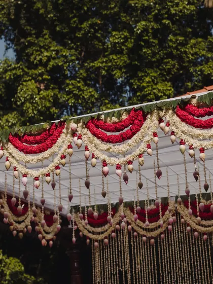 A close-up of the floral decor on the roof of the mandap, featuring red and white flowers.