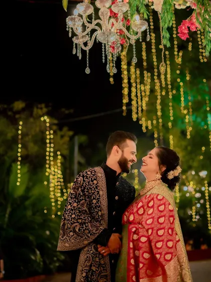 A moment of shared laughter between the couple, captured under a chandelier with a backdrop of warm, cascading lights.