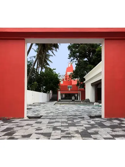 A framed view of the Sai Temple through a bold, red gateway, creating a layered and unfolding experience for the visitor.