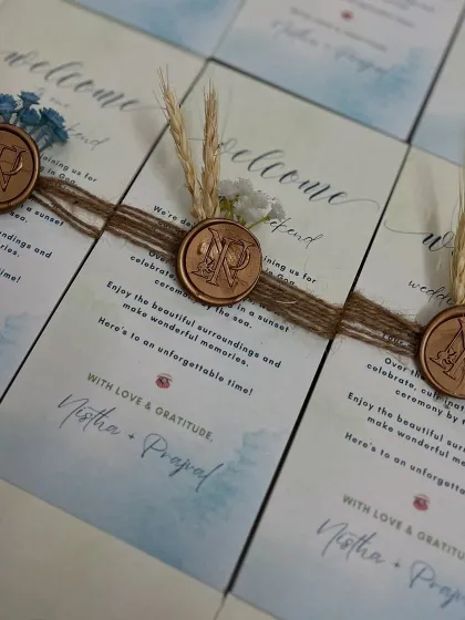 A close-up of the welcome notes from the NP wedding stationery suite. Each note is tied with rustic jute twine and finished with a custom monogrammed wax seal, dried wheat, and delicate flowers for a personal touch.